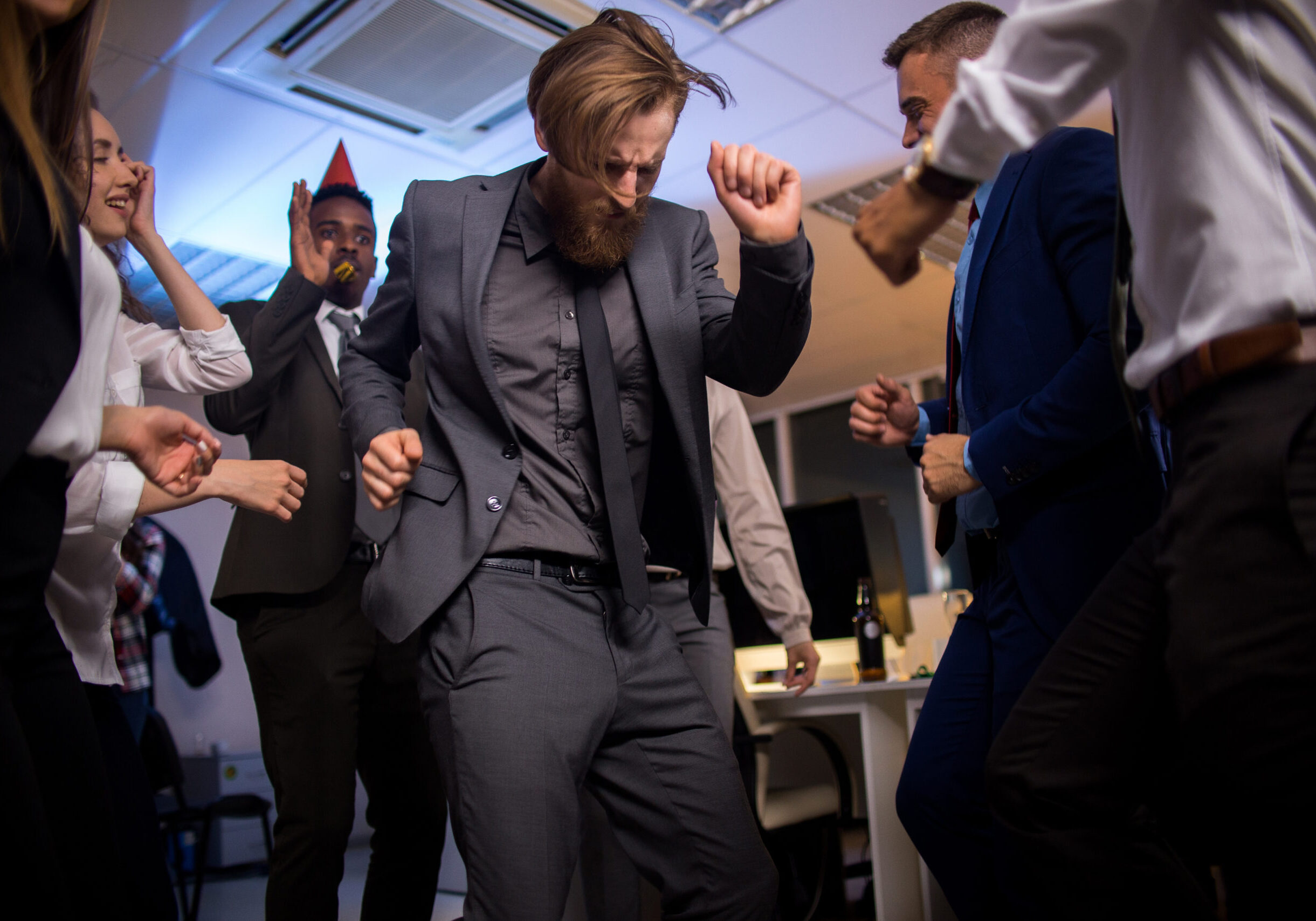 Low angle view of male office worker in elegant suit dancing with colleagues on  corporate party